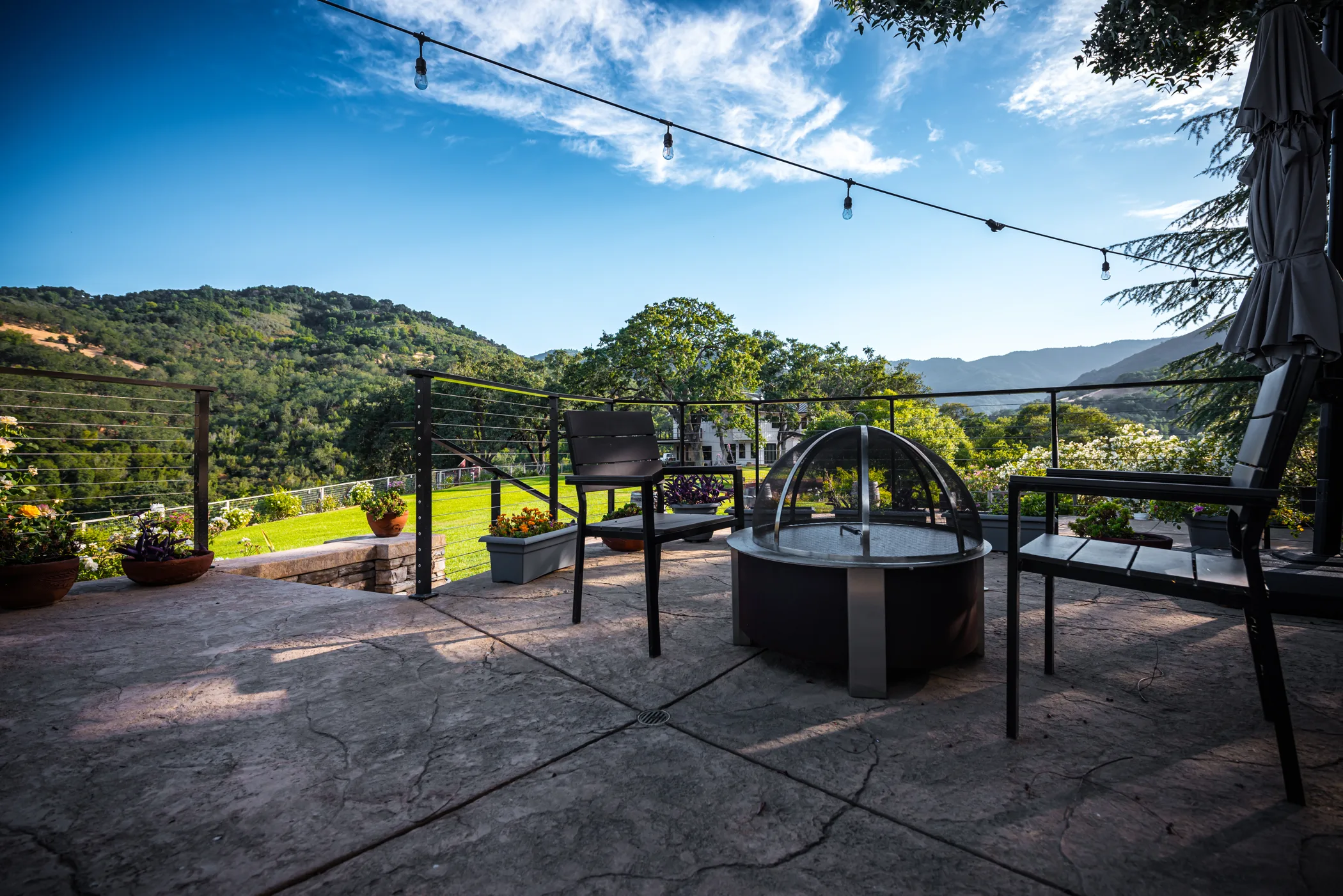 Fire pit and string lights with a view of the lawn and hillside
